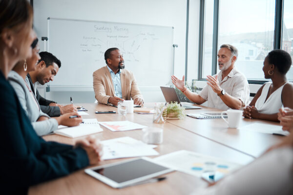 Shot of a group of staff listening to their boss during a business meeting.